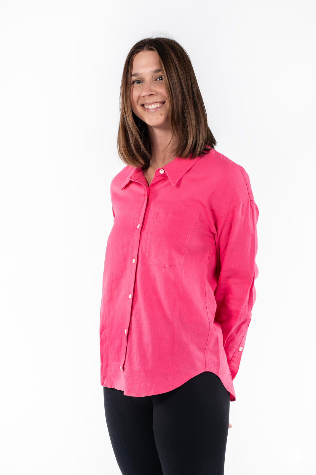 Woman smiling wearing SweetTops Classic Linen Shirt in bright pink with button front and chest pocket standing on white background