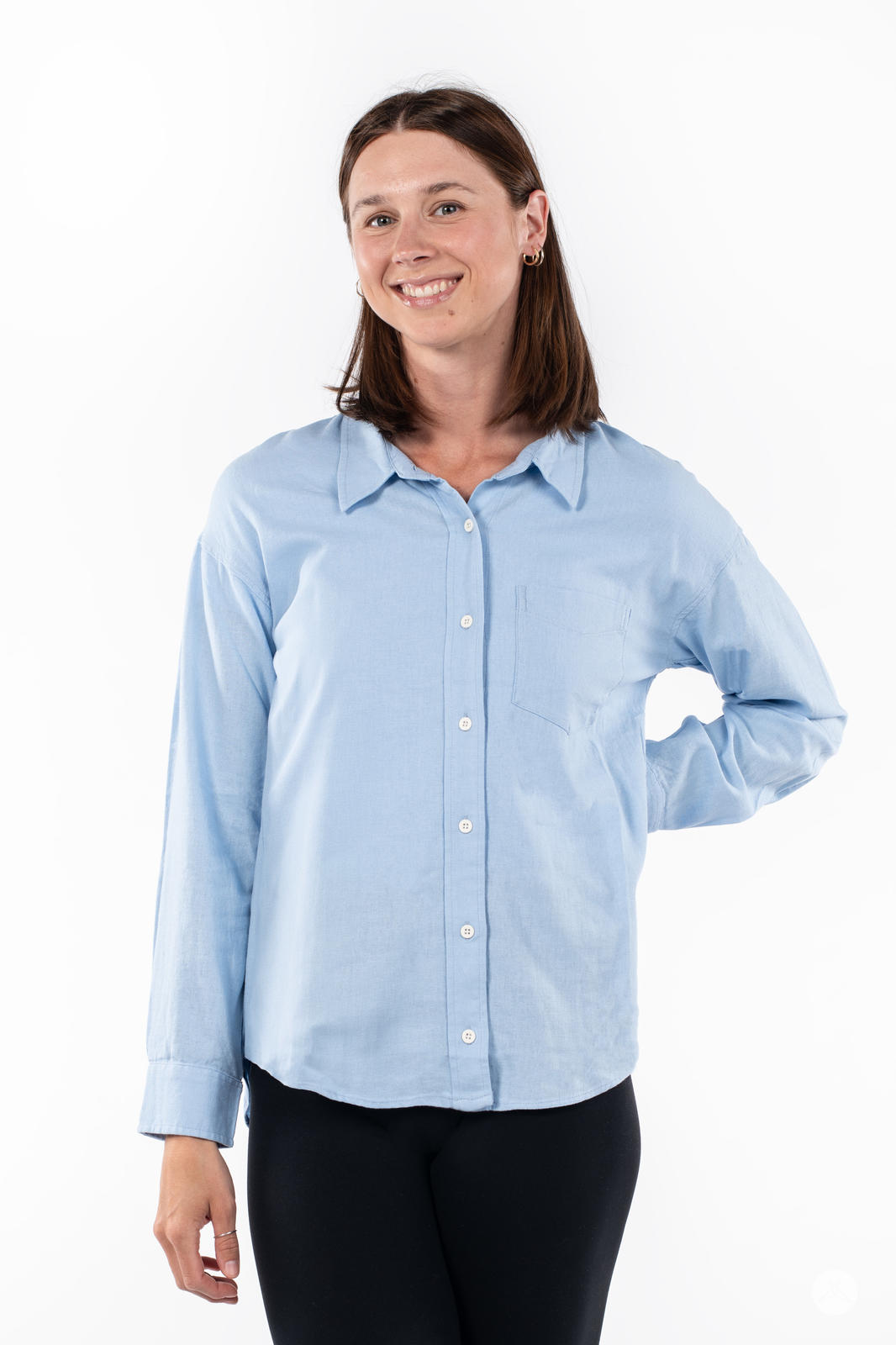 Smiling woman wearing SweetTops Classic Linen Shirt in light blue with long sleeves and front chest pocket on white background