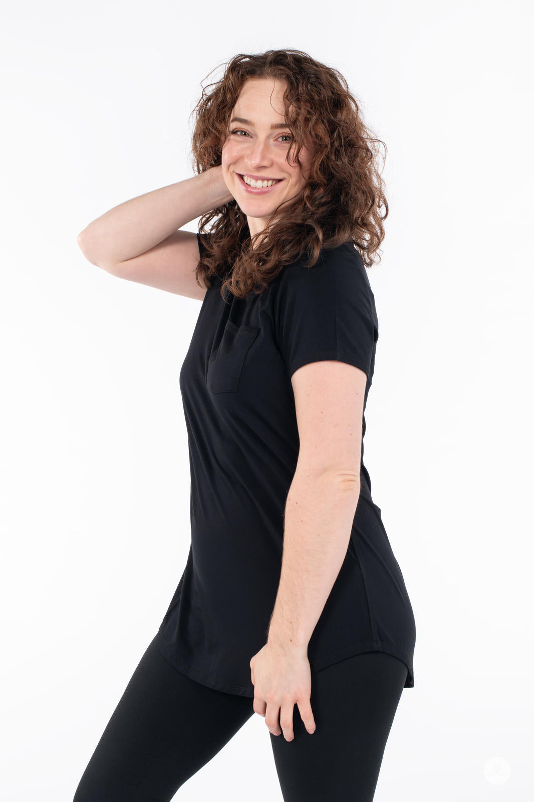 Smiling woman posing in SweetTops Crew Neck Pocket Tee in black showing side view and relaxed fit design