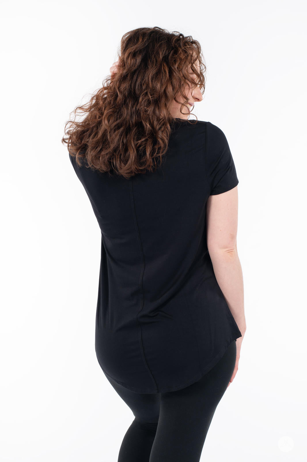 Woman posing from behind wearing SweetTops Crew Neck Pocket Tee in black with short sleeves and relaxed fit