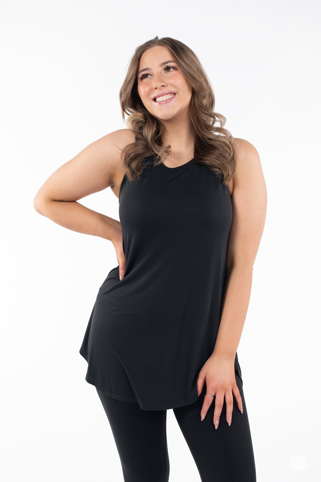 Smiling woman wearing SweetTops High Neck Swing Tank in black paired with black leggings on white background