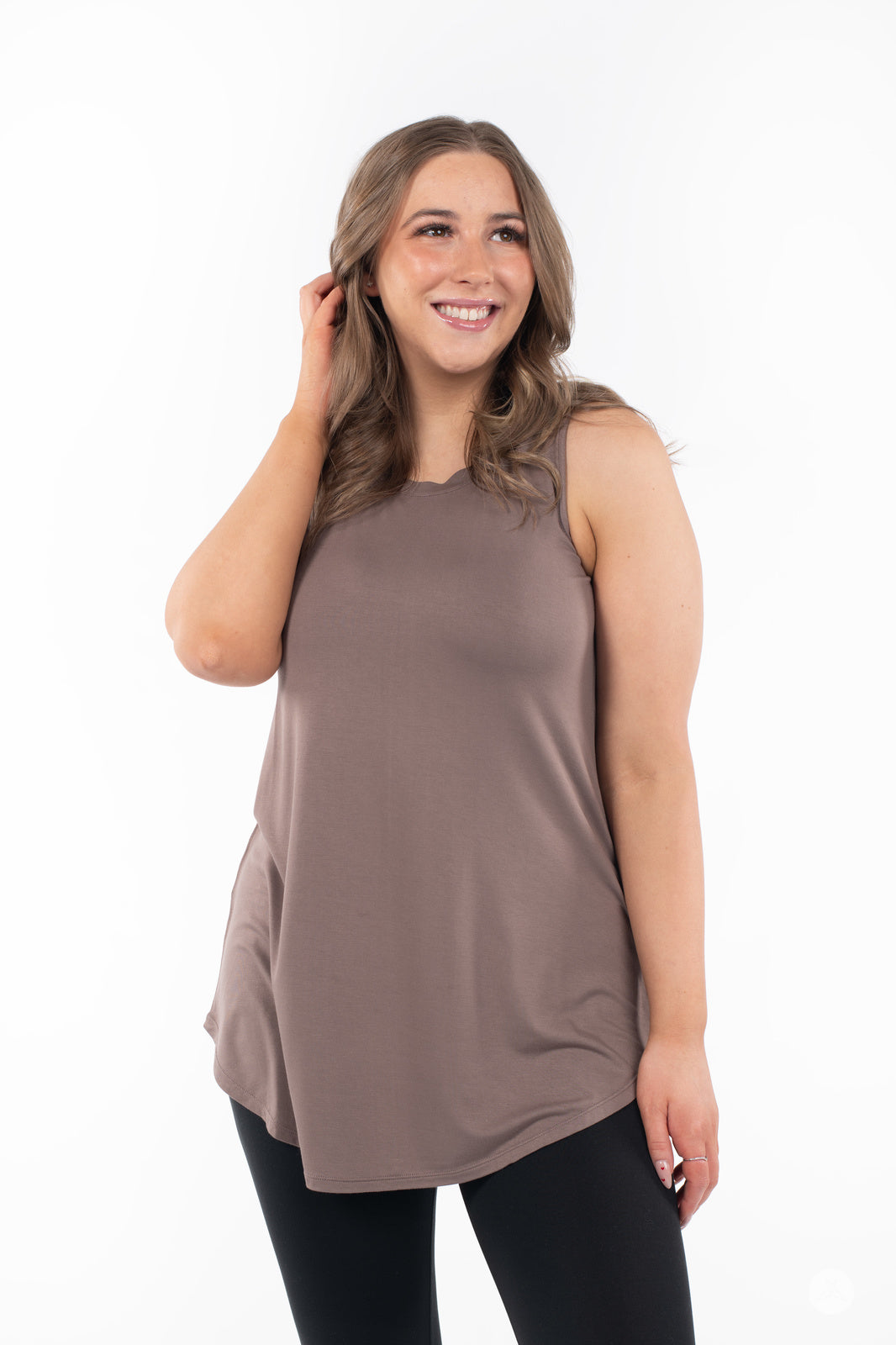 Smiling woman wearing SweetTops High Neck Swing Tank in Latte with black leggings on white background