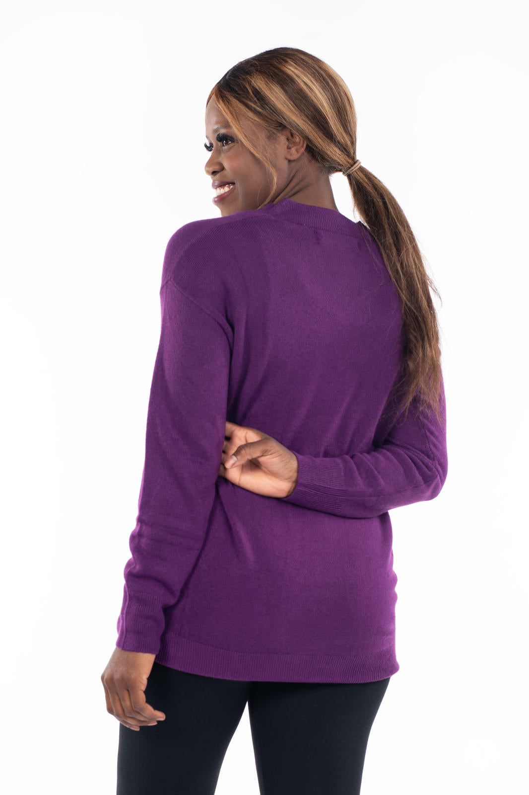 Woman smiling wearing SweetTops Soft Knit V-Neck Sweater in deep purple shown from the back with ribbed cuffs and hem