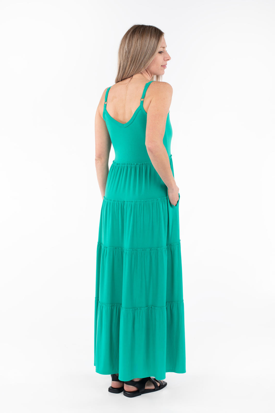 Woman wearing SweetTops The Summer Tiered Dress in vibrant green with adjustable straps and flowing tiered maxi skirt viewed from back
