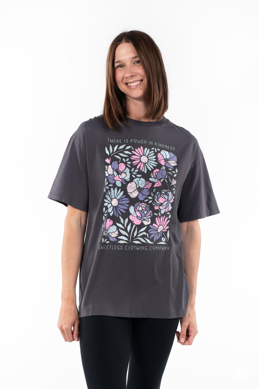 Smiling woman wearing SweetTops Vintage Graphic Tee in charcoal with floral artwork and kindness affirmation text means positive vibes