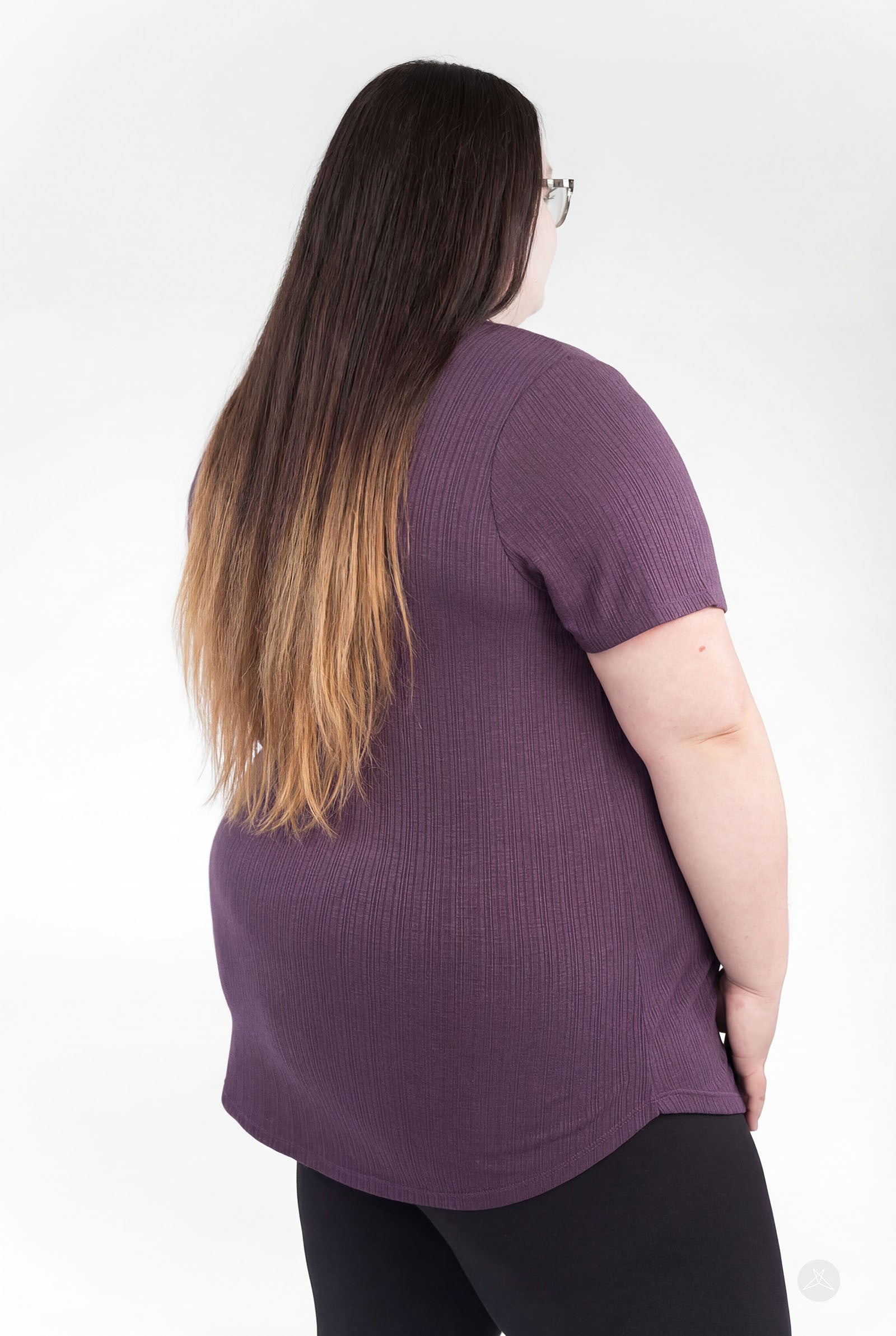 Plus-size model showing back of purple The Soft Ribbed Tee by SweetLegs Canada with rib-knit fabric and curved hem
