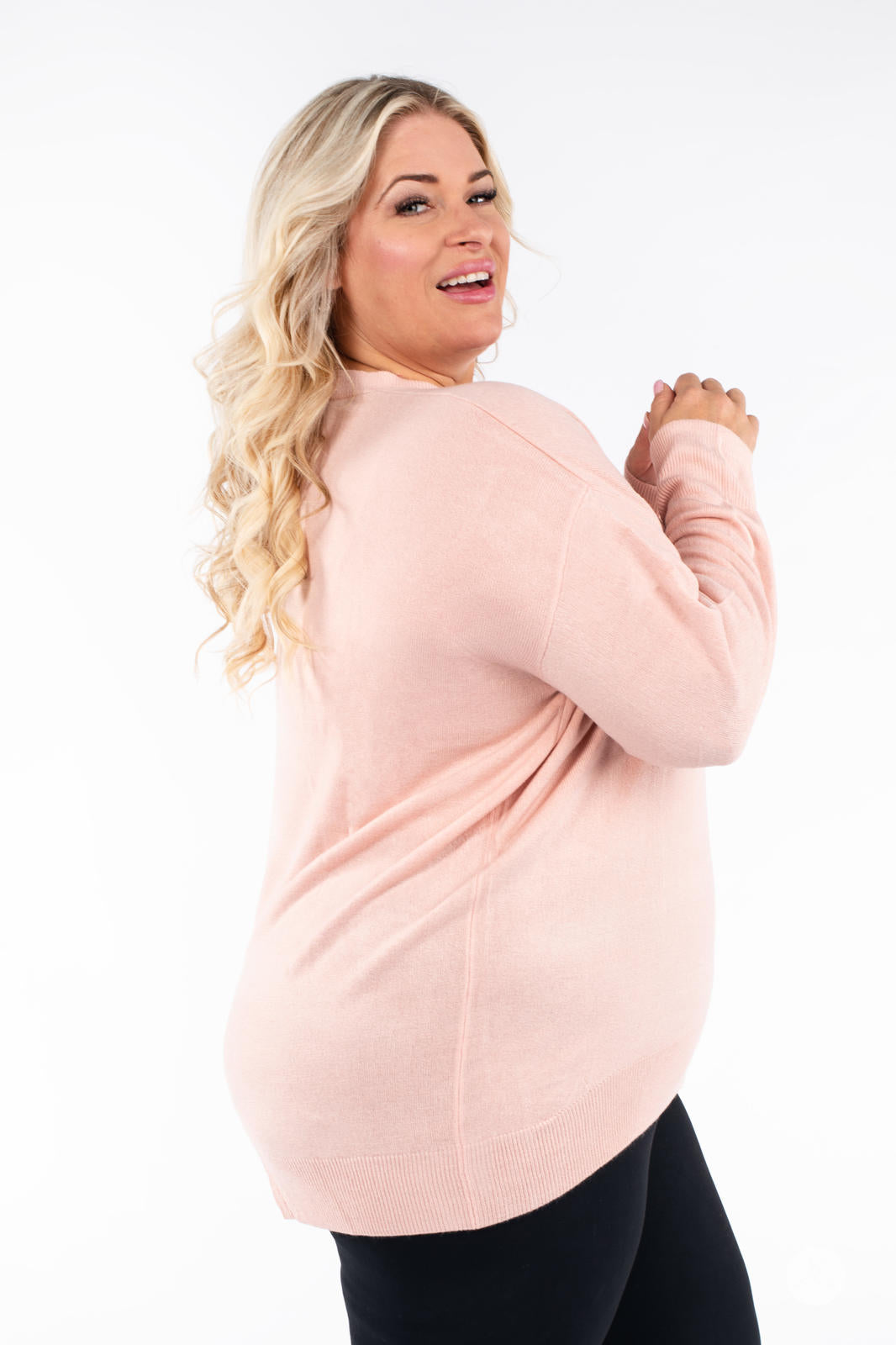 Plus size model turning back wearing SweetTops Soft Knit Crew Neck Sweater in soft pink with cozy fit