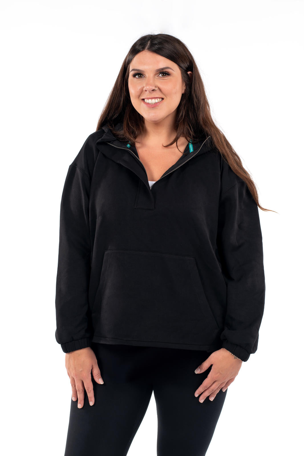 Smiling woman wearing black SweetTops All Day Hoodie with half zip and front pocket on white background