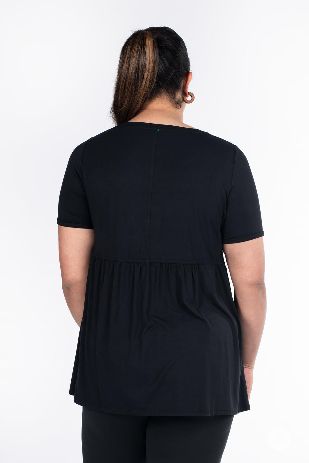 Plus-size woman wearing black Babydoll Tee by SweetLegs Canada with short sleeves and babydoll cut back view