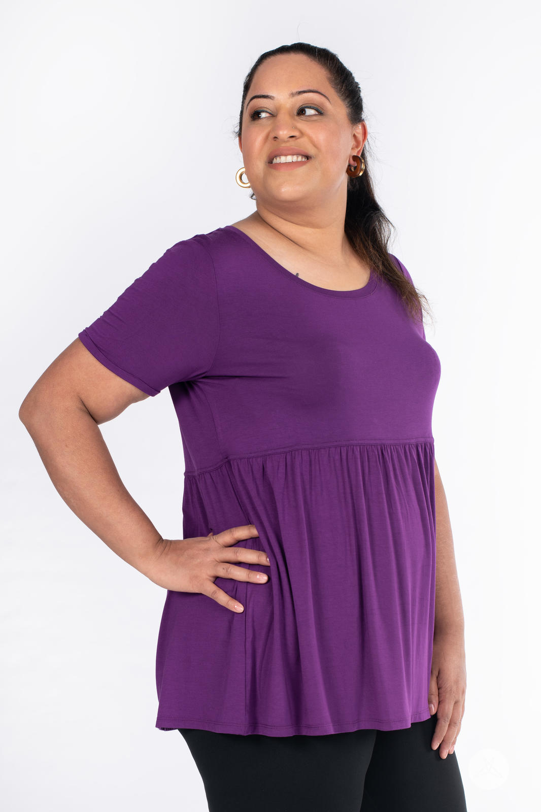Plus-size woman wearing purple Babydoll Tee by SweetLegs Canada with round neckline and short sleeves looking to side
