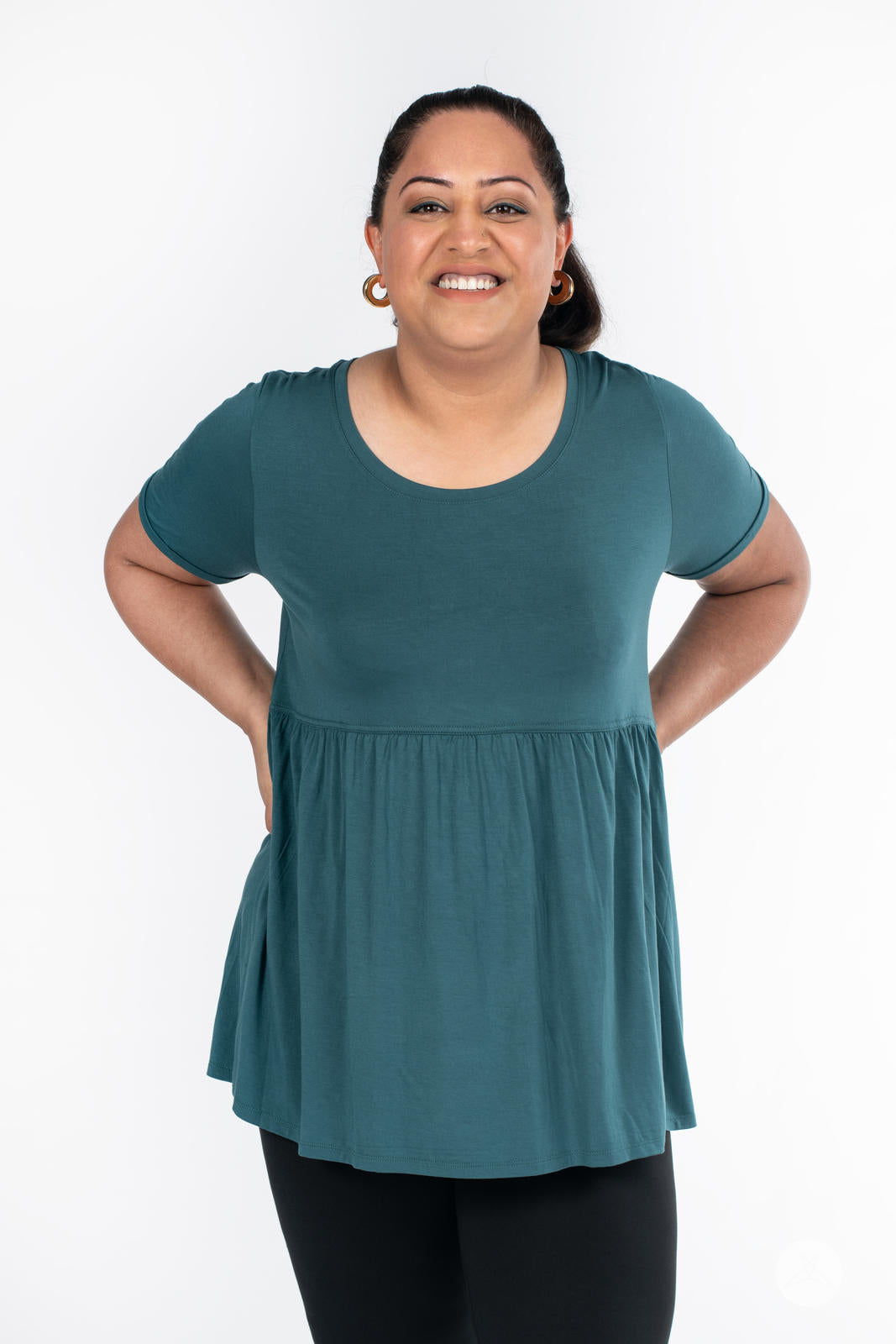Smiling woman wearing teal Babydoll Tee by SweetLegs Canada with short sleeves and loose babydoll fit front view