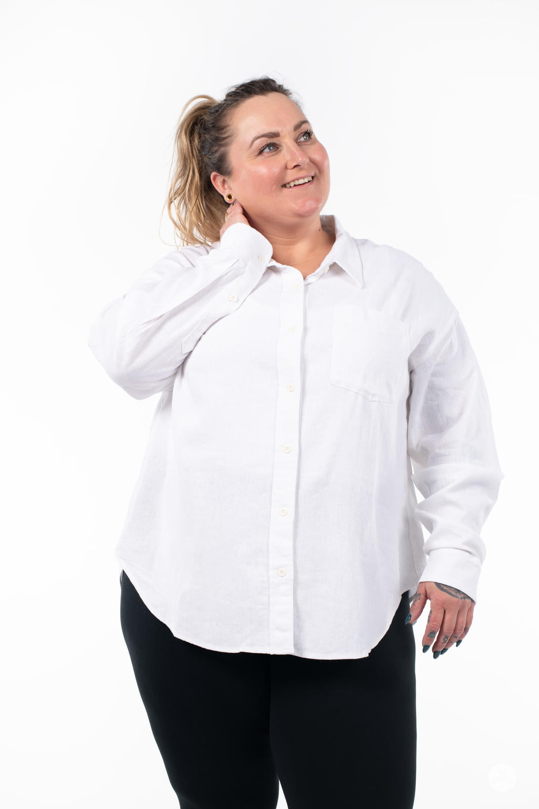 Plus-size model wearing SweetTops Classic Linen Shirt in white with chest pocket and relaxed fit smiling and looking up