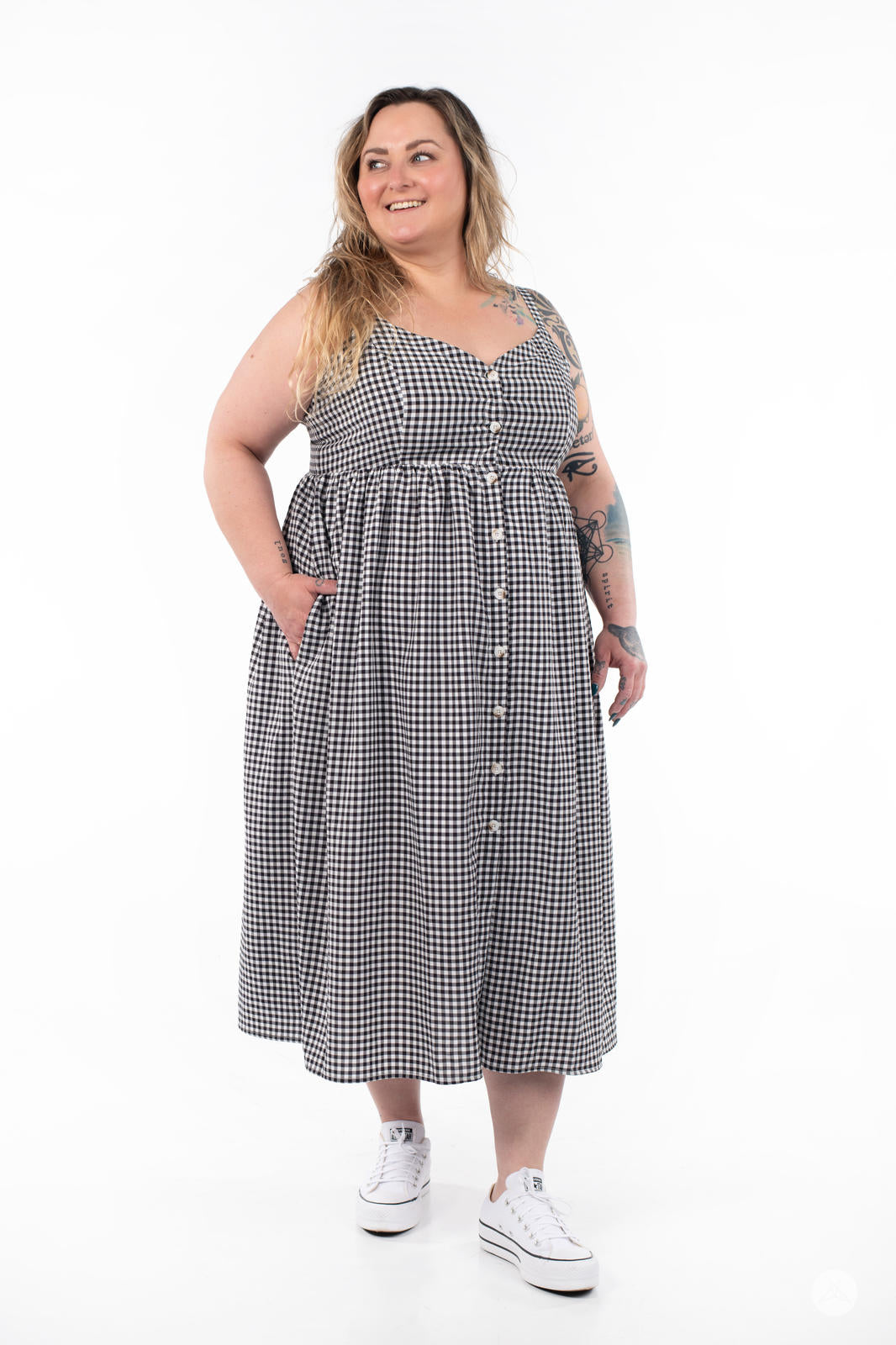 Plus-size model smiling and wearing SweetTops Gingham Dress in black with button front and side pockets standing on white background