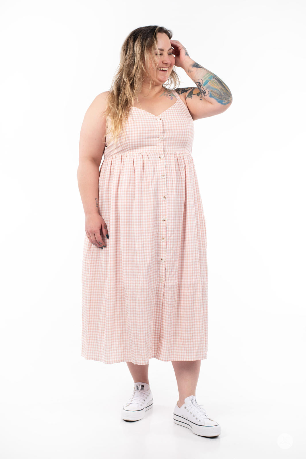 Plus-size model smiling and wearing SweetTops Gingham Dress in soft pink with button front and A-line silhouette