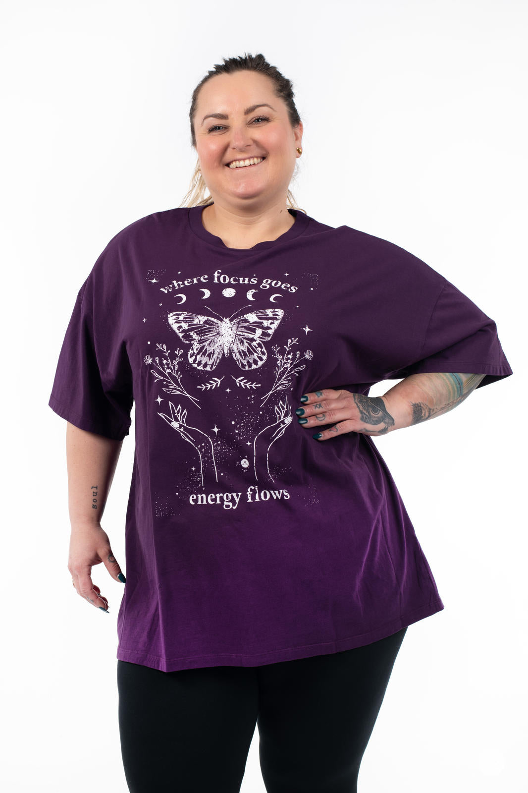 Smiling woman wearing SweetTops Vintage Graphic Tee in purple with butterfly, floral art, and positive affirmation text design