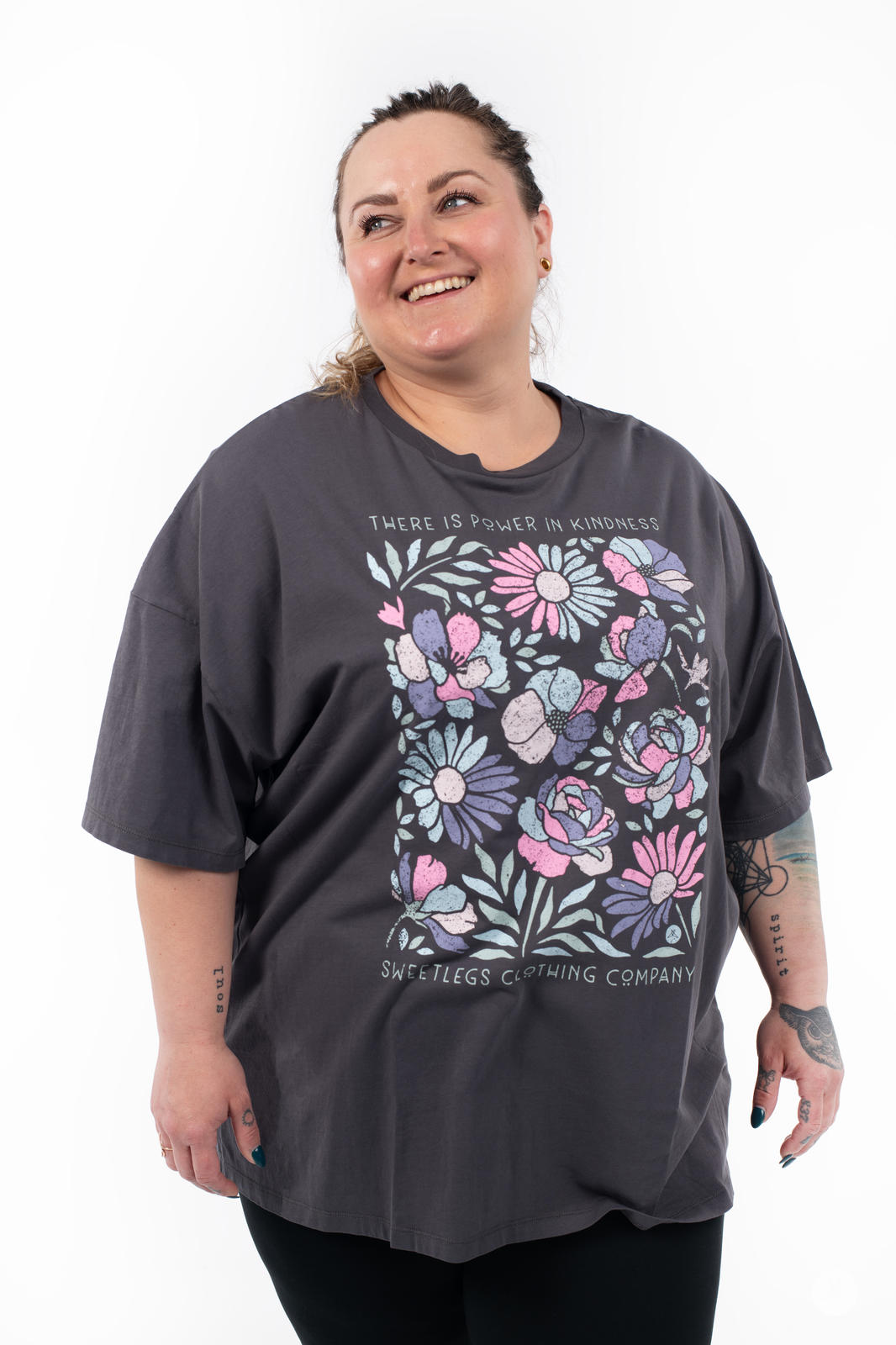 Woman wearing SweetTops Vintage Graphic Tee in charcoal with pastel floral art and kindness affirmation by SweetLegs