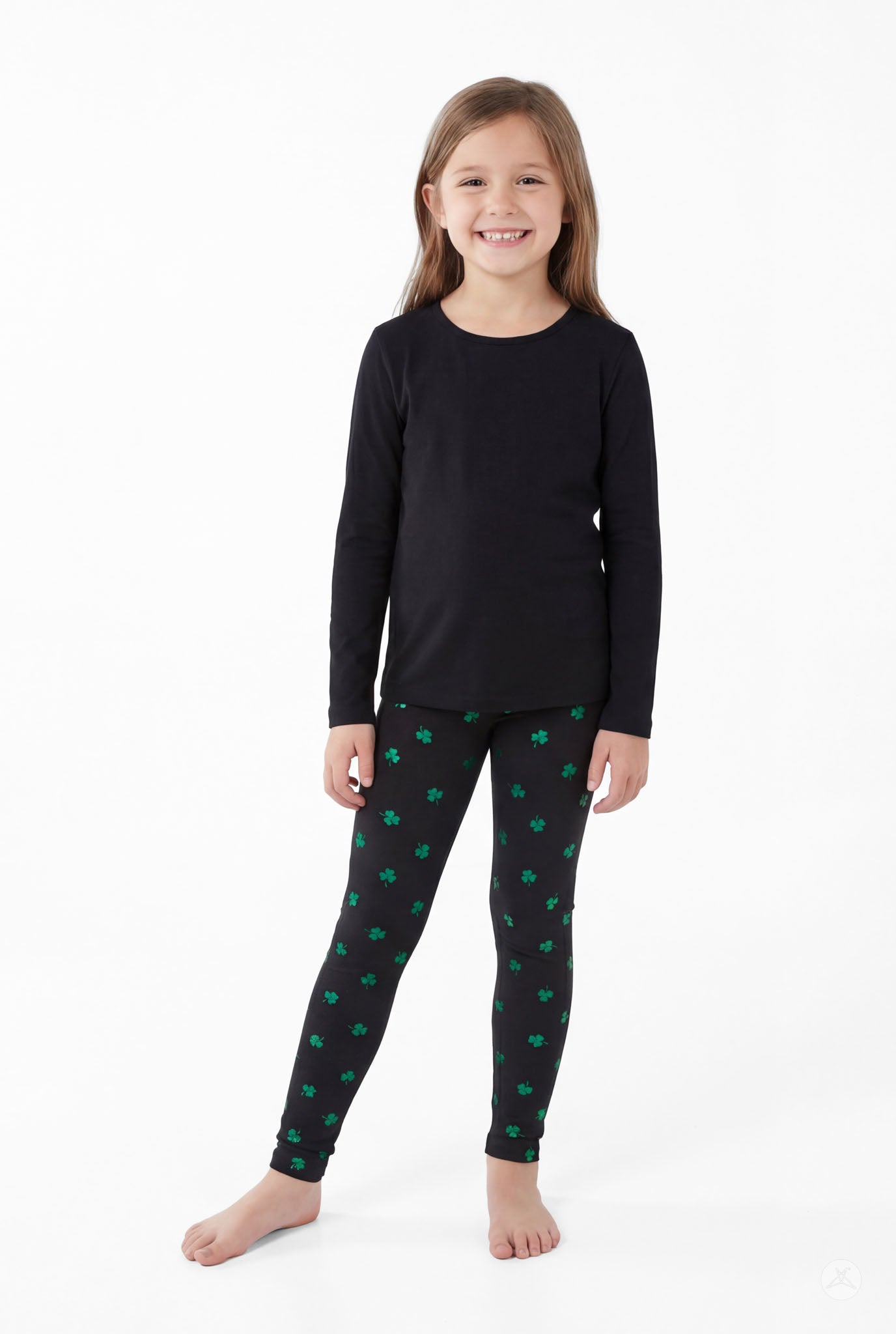 Smiling girl wearing Lucky Glow Kids black leggings with green shamrocks by SweetLegs and a plain black long sleeve top