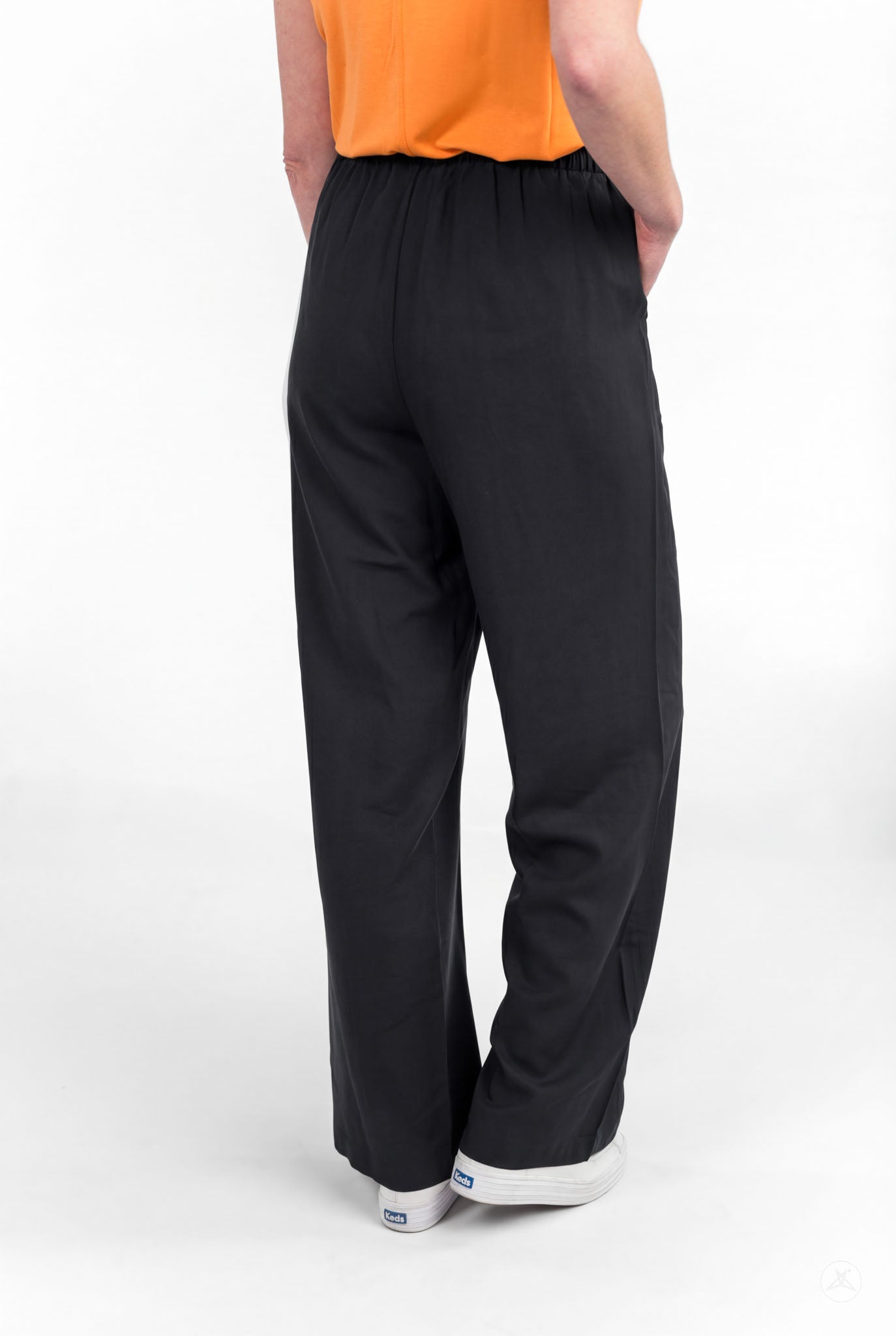 Person standing with hands in pockets wearing black Breeze Wide-Leg Pant by sweetlegs on white background