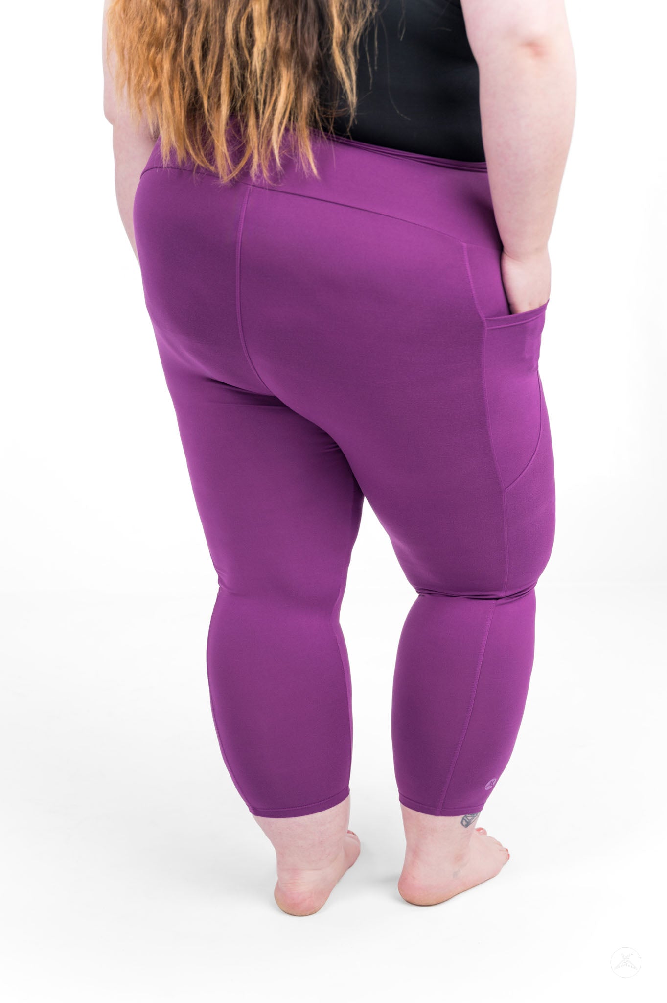 Plus size model standing barefoot wearing sweetlegs Deep Plum High-Waisted Pocket Crops shown from back with hands in pockets