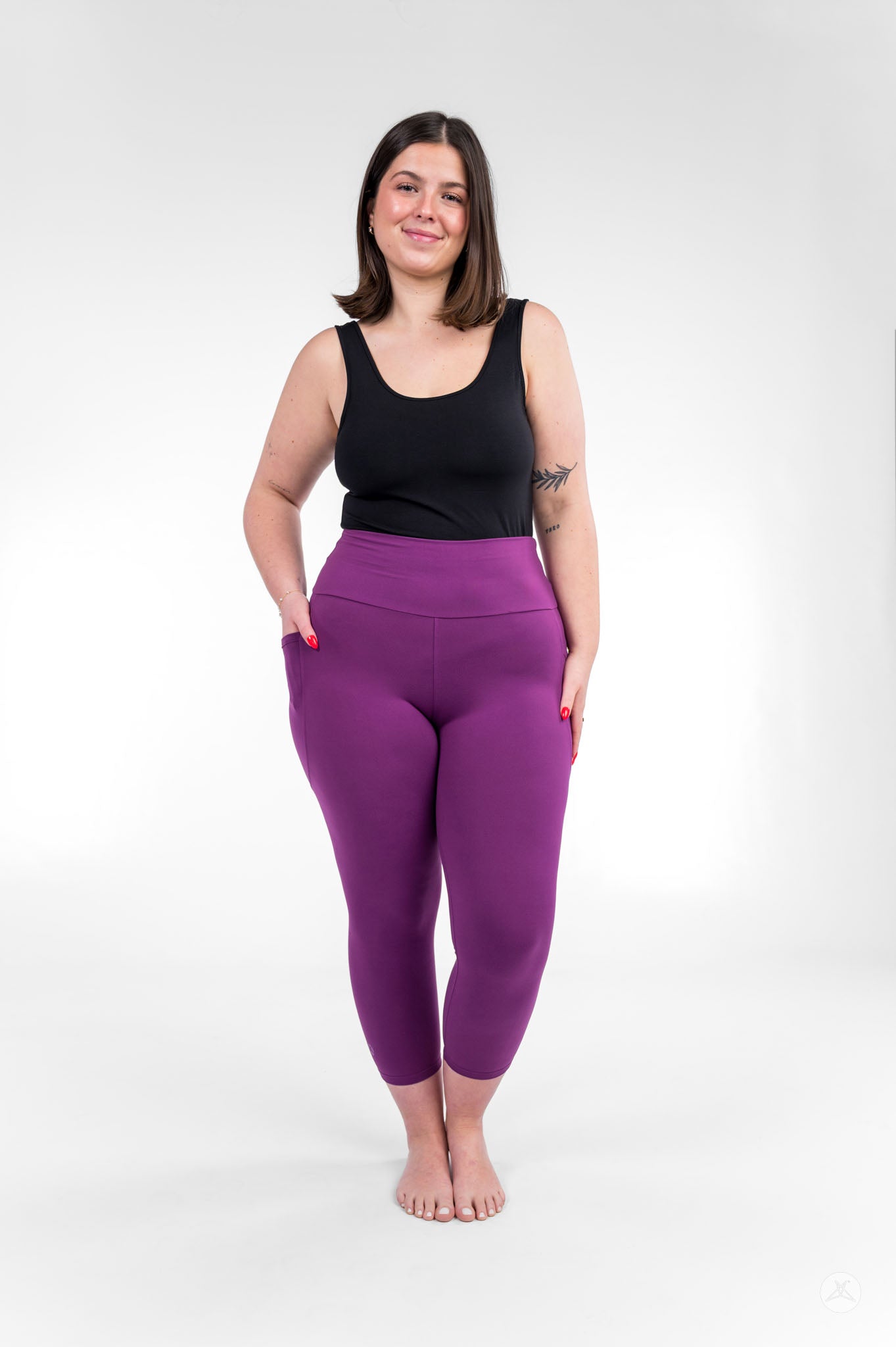 Woman smiling barefoot wearing sweetlegs Deep Plum High-Waisted Pocket Crops with black tank top and hands in pockets