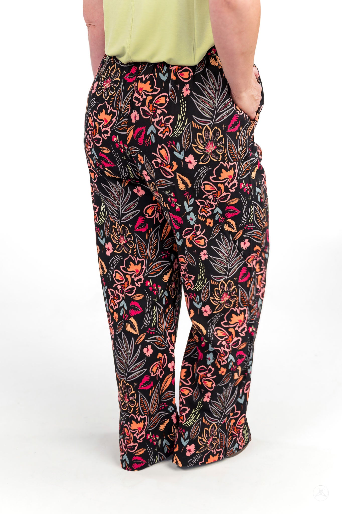Person standing with hands in pockets wearing floral patterned Breeze Wide-Leg Pant by sweetlegs on white background