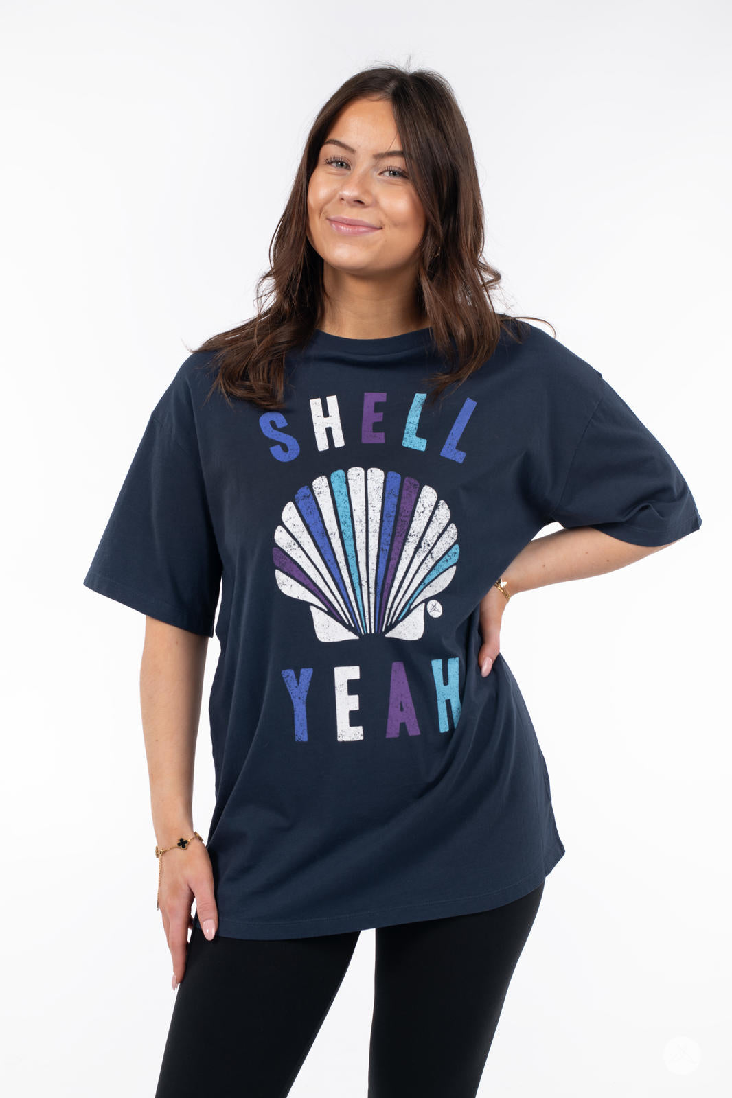 Smiling woman wearing SweetTops Vintage Graphic Tee in navy with colorful shell design and playful "Shell Yeah" text