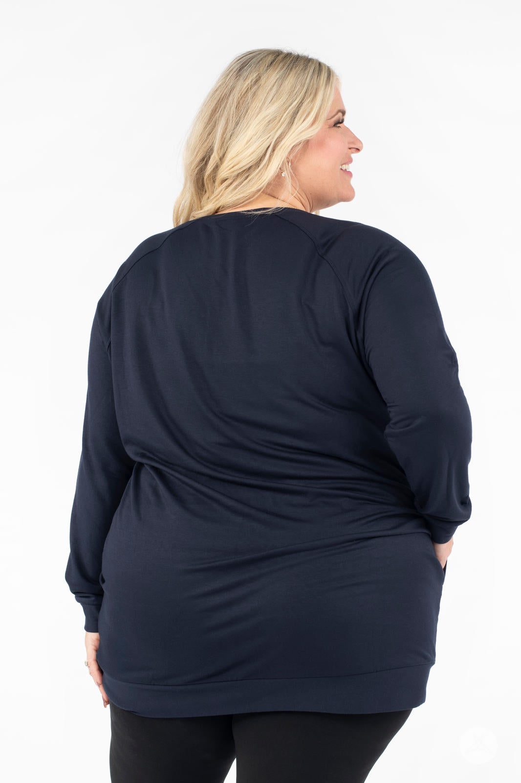 Plus-size model smiling wearing SweetLegs Canada Everyday Raglan Pullover in navy shown from the back with hands in pockets