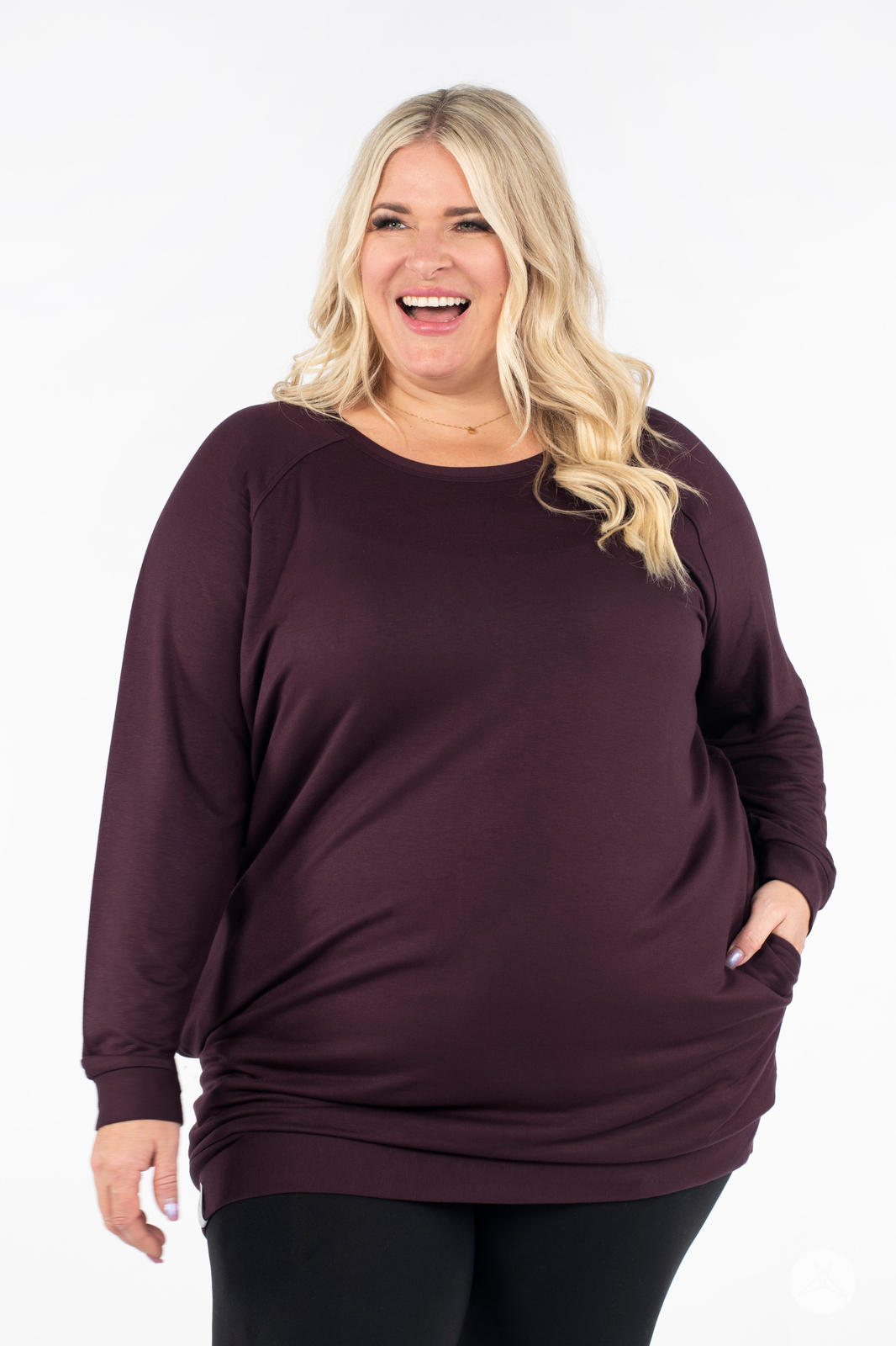 Plus-size model smiling wearing SweetLegs Canada Everyday Raglan Pullover in deep plum with hand in pocket