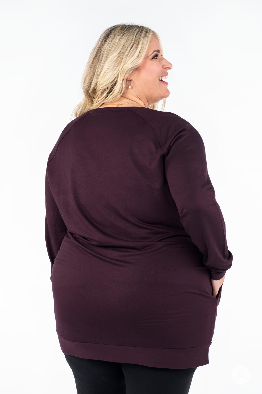 Plus-size model facing away wearing SweetLegs Canada Everyday Raglan Pullover in rich plum with hands in pockets