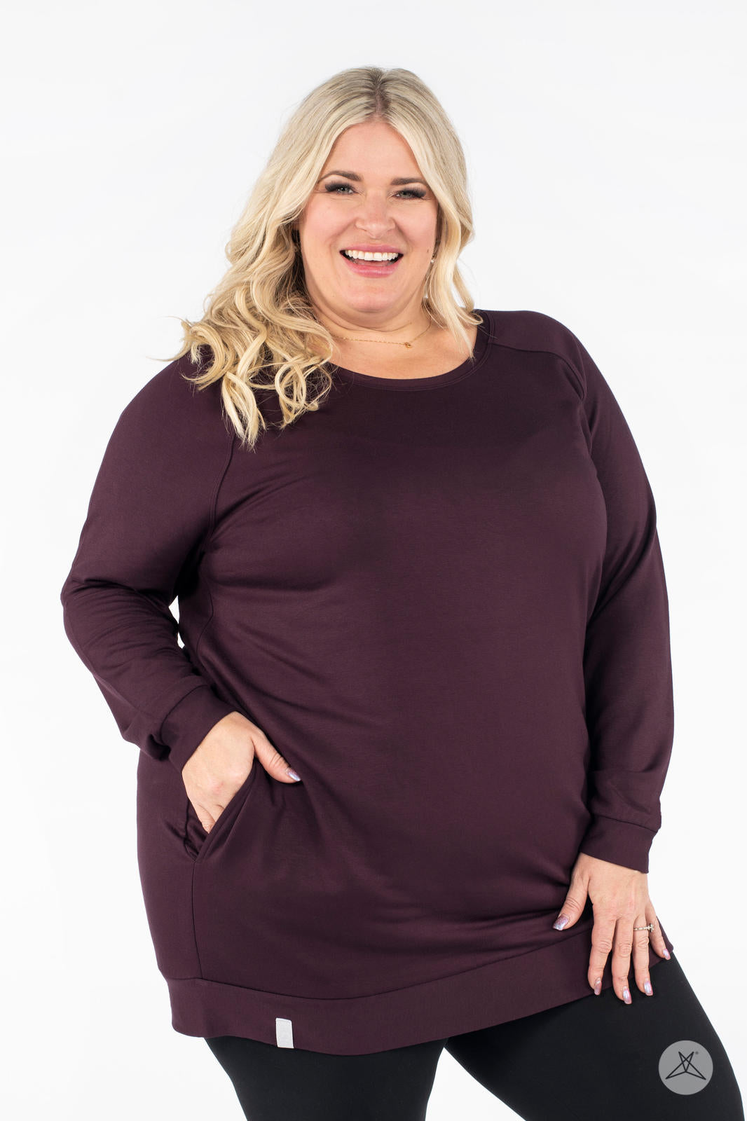 Plus-size model smiling wearing SweetLegs Canada Everyday Raglan Pullover in deep plum with one hand in pocket