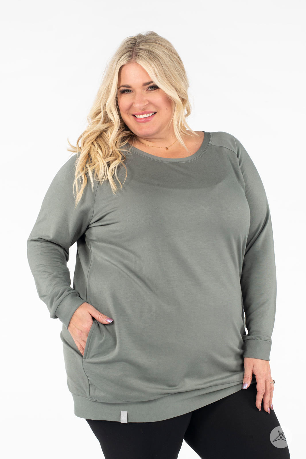 Plus-size model smiling with hand in pocket wearing SweetLegs Canada Everyday Raglan Pullover in muted green