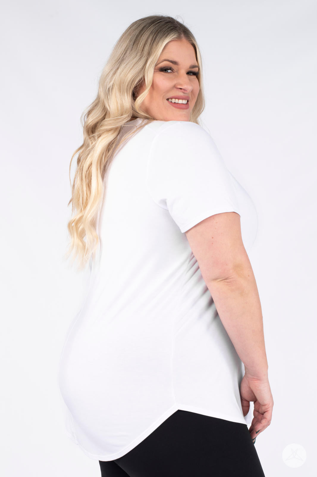 Plus size model smiling over shoulder wearing white Classic Tee by SweetLegs Canada with short sleeves and curved hem