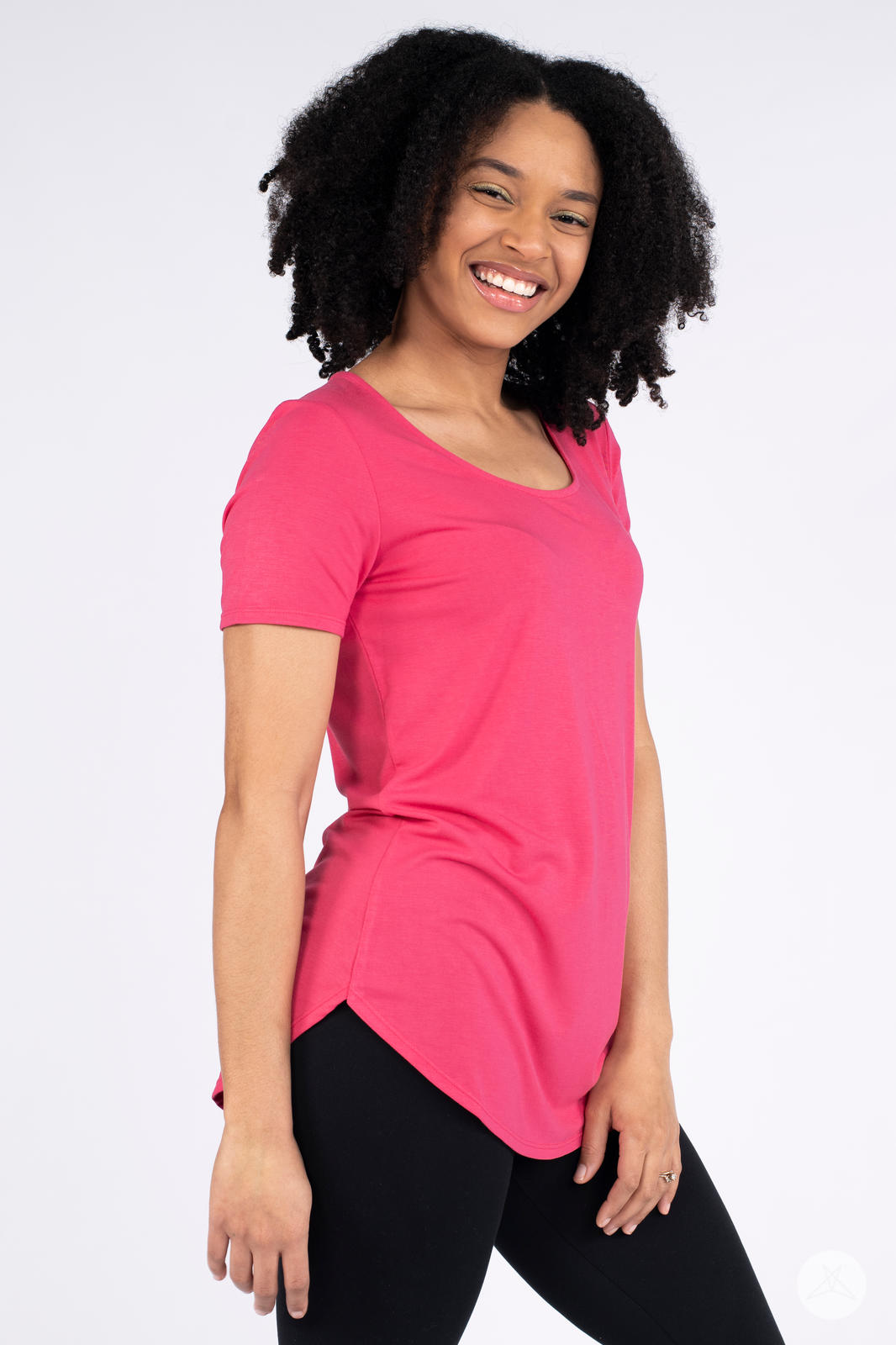 Smiling woman wearing hot pink Classic Tee by SweetLegs Canada with scoop neck and curved hem side view