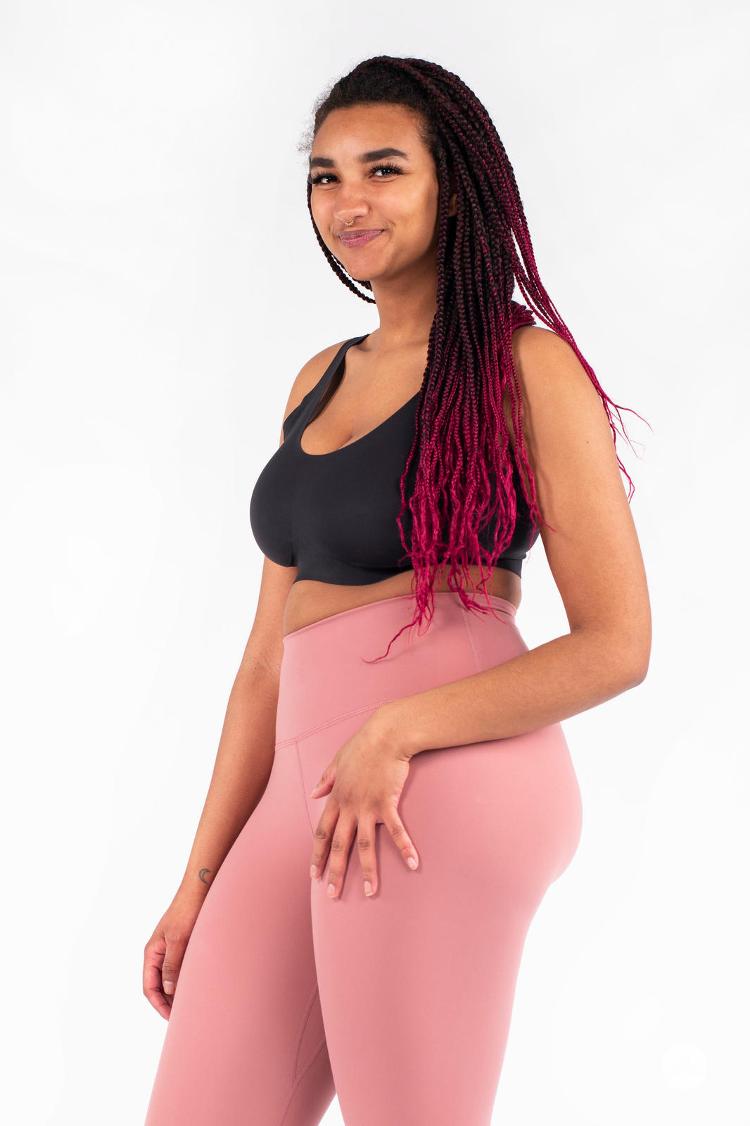 Smiling woman wearing pink Free Motion Crops by Athleisure SweetLegs collection standing against white background