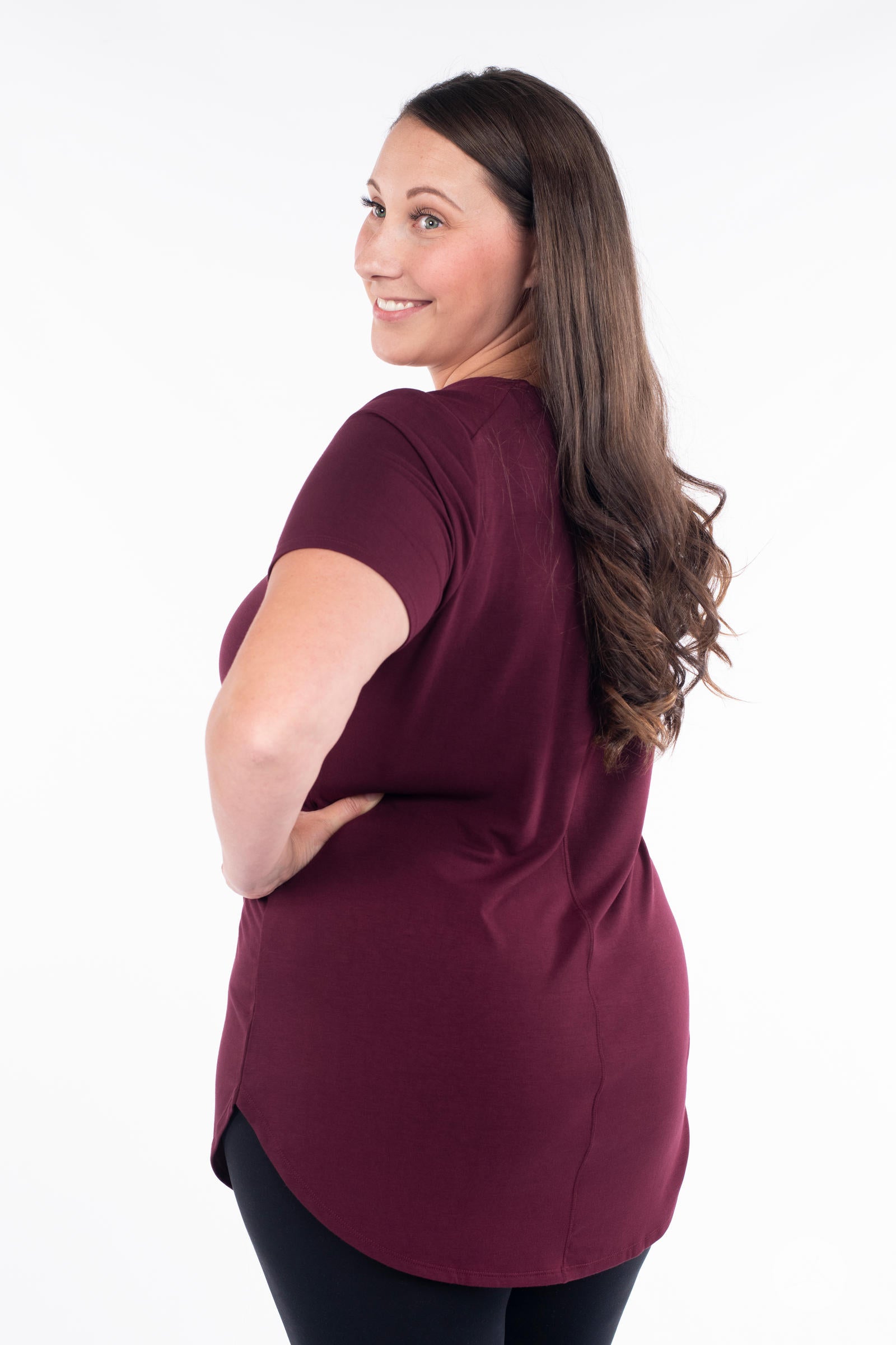 Plus size woman wearing maroon Classic Tee by SweetLegs Canada with short sleeves and curved high-low hem back view