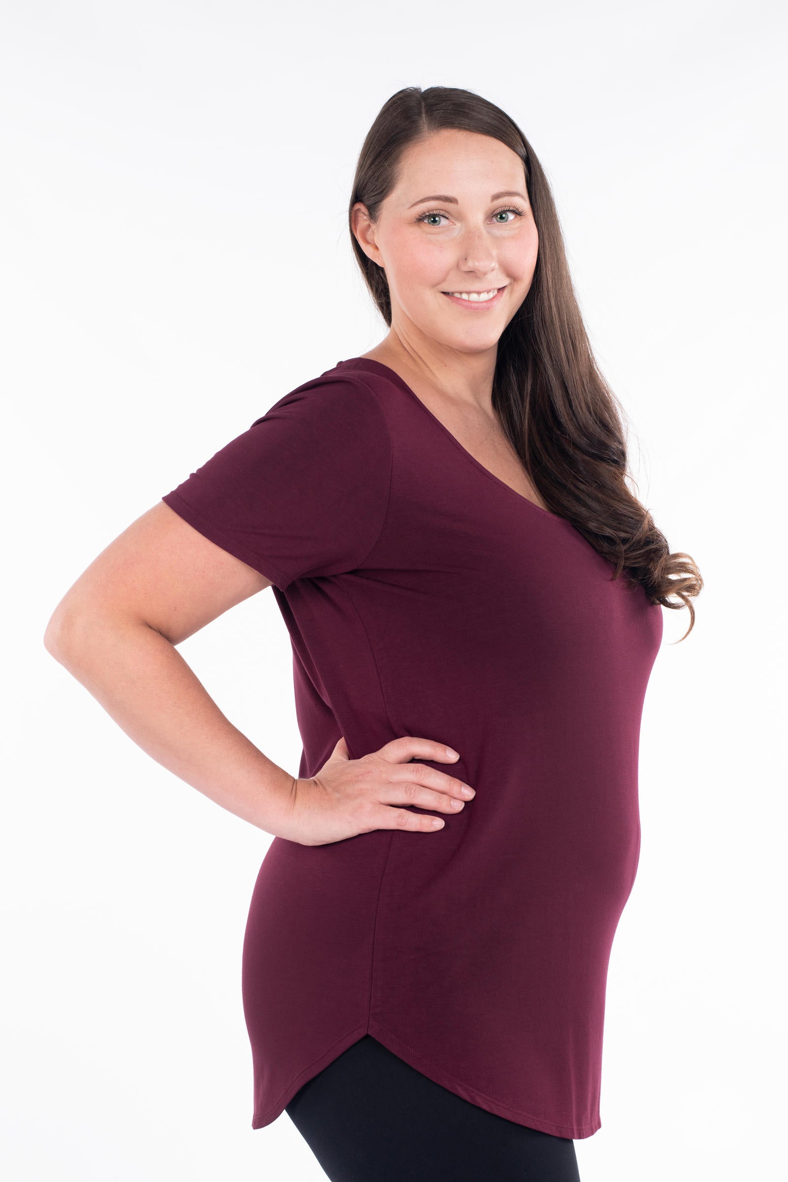 Woman posing in maroon Classic Tee by SweetLegs Canada with short sleeves and rounded curved hem side view