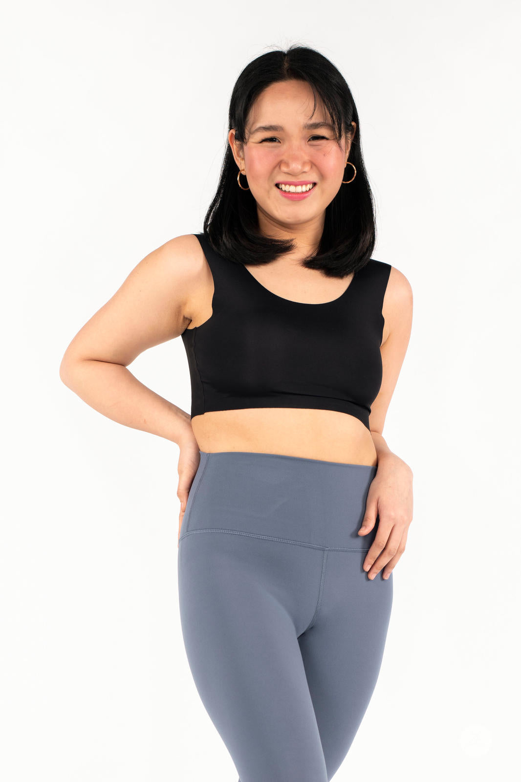 Smiling woman wearing gray Free Motion Crops by Athleisure SweetLegs collection with hand on hip on white background