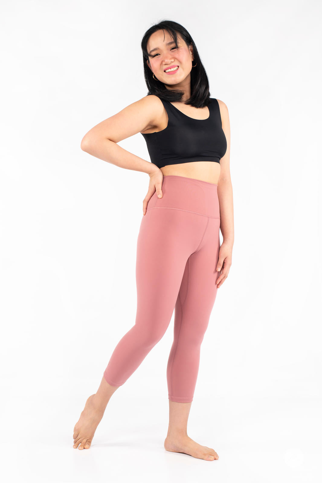 Woman smiling wearing pink Free Motion Crops by Athleisure SweetLegs collection with black crop top on white background