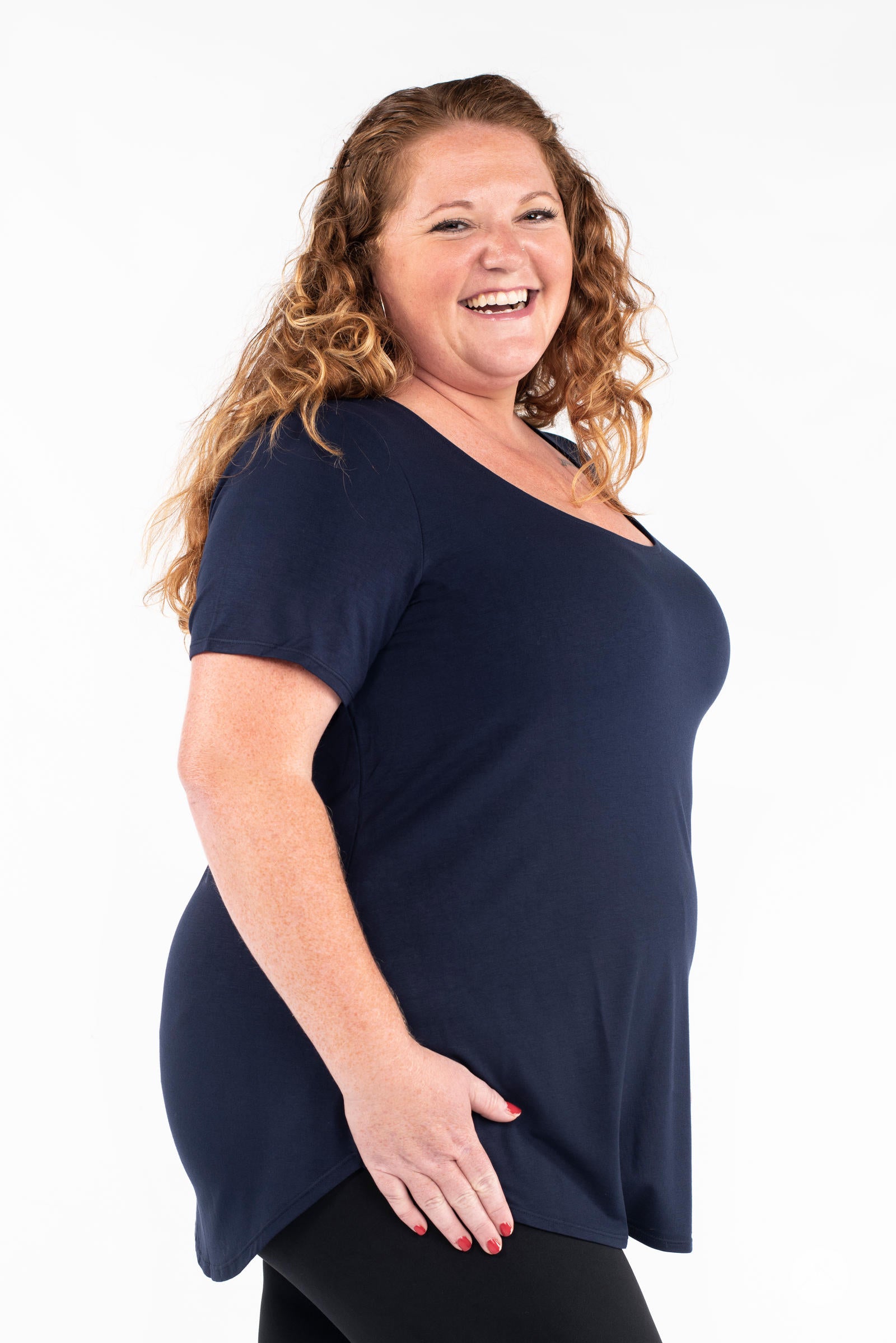 Curvy woman smiling wearing navy Classic Tee by SweetLegs Canada with scoop neck and relaxed fit side profile