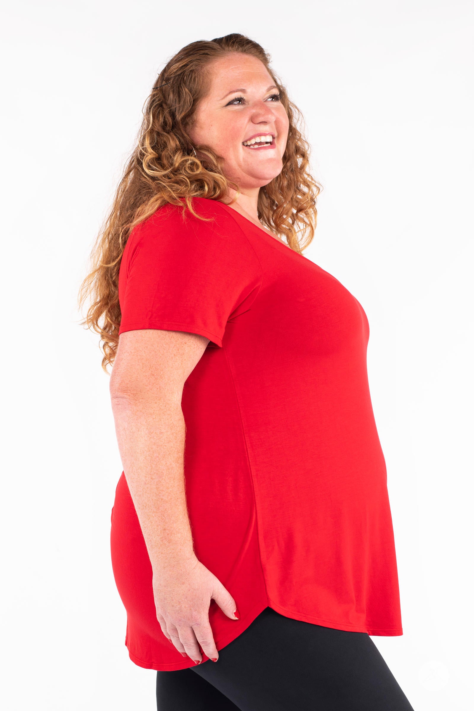 Plus size model smiling wearing red Classic Tee by SweetLegs Canada with short sleeves and relaxed fit in side profile view