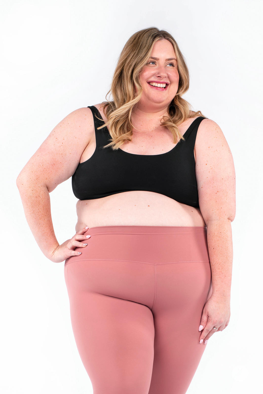 Plus size model smiling wearing rose Free Motion Crops by Athleisure SweetLegs collection with black sports bra
