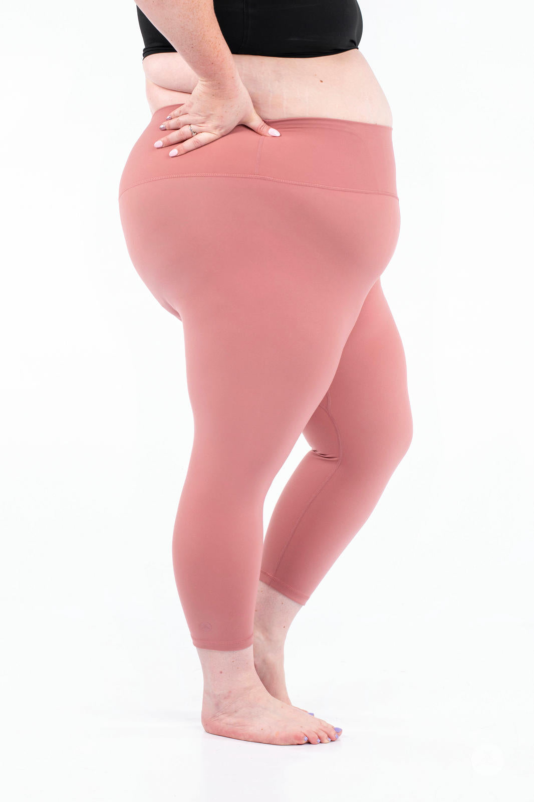 Plus size model wearing dusty rose Free Motion Crops by Athleisure SweetLegs collection standing barefoot side view