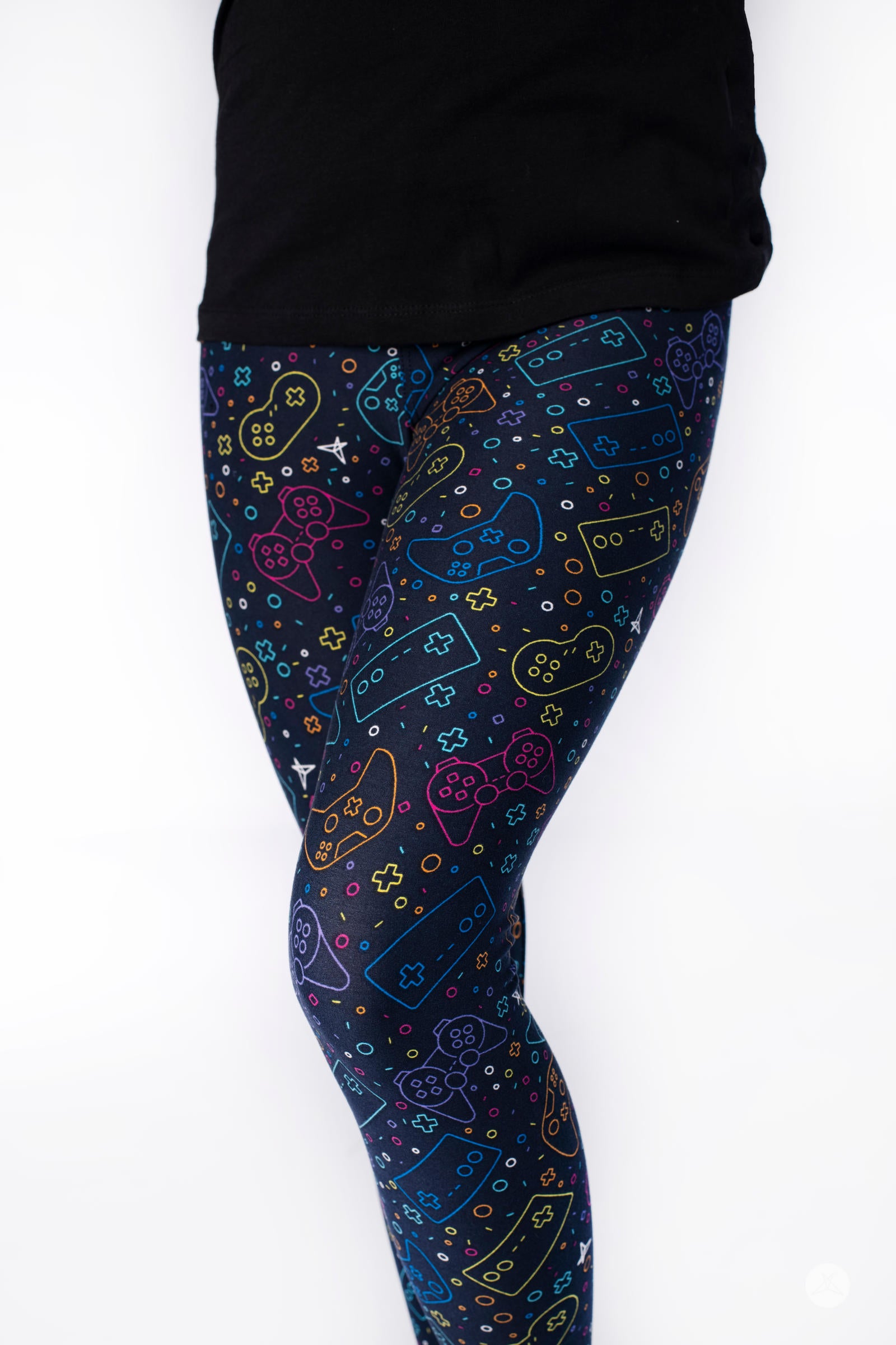 Close-up of child wearing SweetLegs Level Up Kids leggings with colorful gaming controller outlines on navy background
