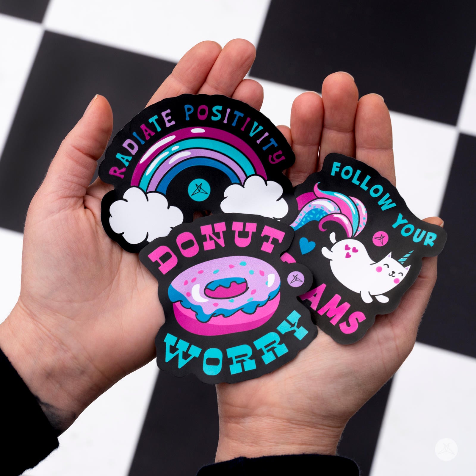 Hands holding SweetLegs Happiness Sticker Pack featuring colorful donut, rainbow, and unicorn designs with positive phrases