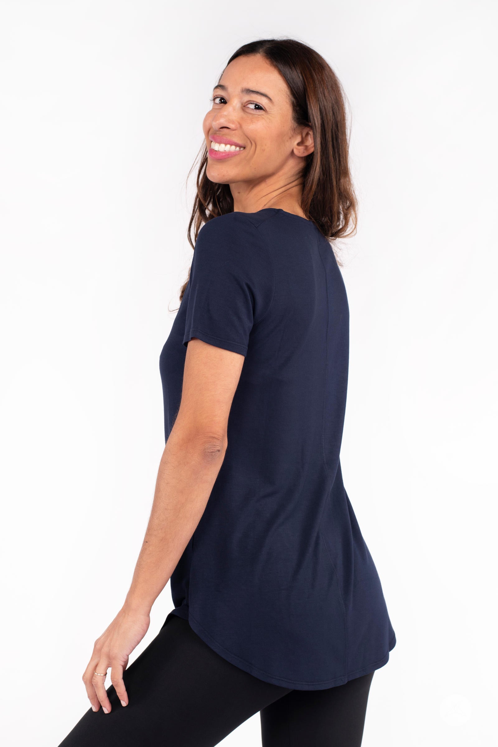 Smiling woman wearing navy Classic Tee by SweetLegs Canada with short sleeves and high to low hem back view