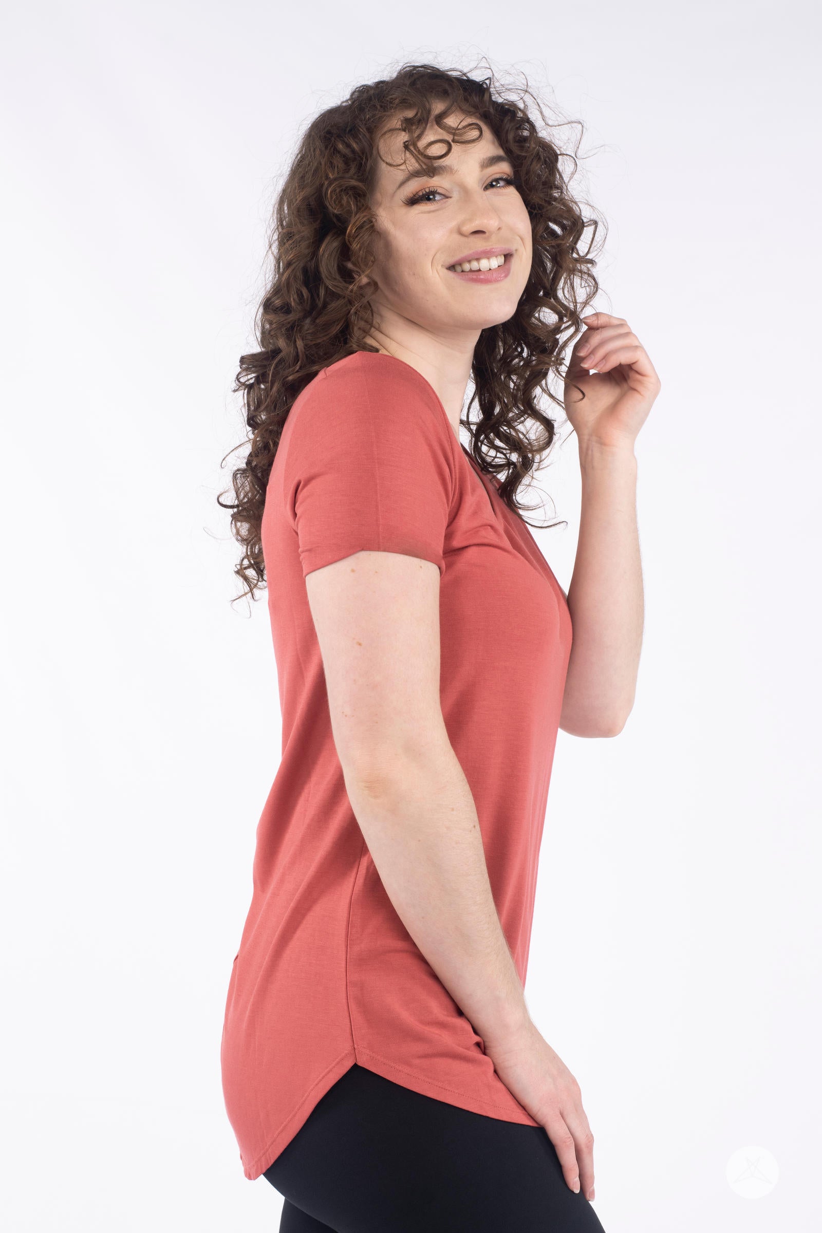 Curly haired woman smiling wearing rust Classic Tee by SweetLegs Canada with short sleeves and side view
