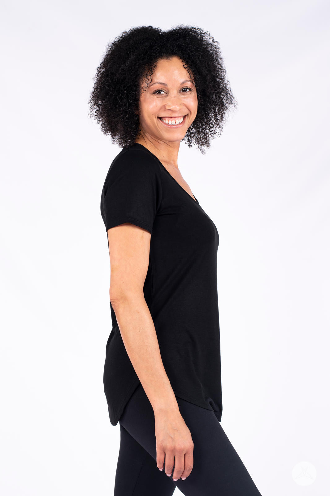 Woman smiling wearing black Classic Tee by SweetLegs Canada with scoop neck and side profile view