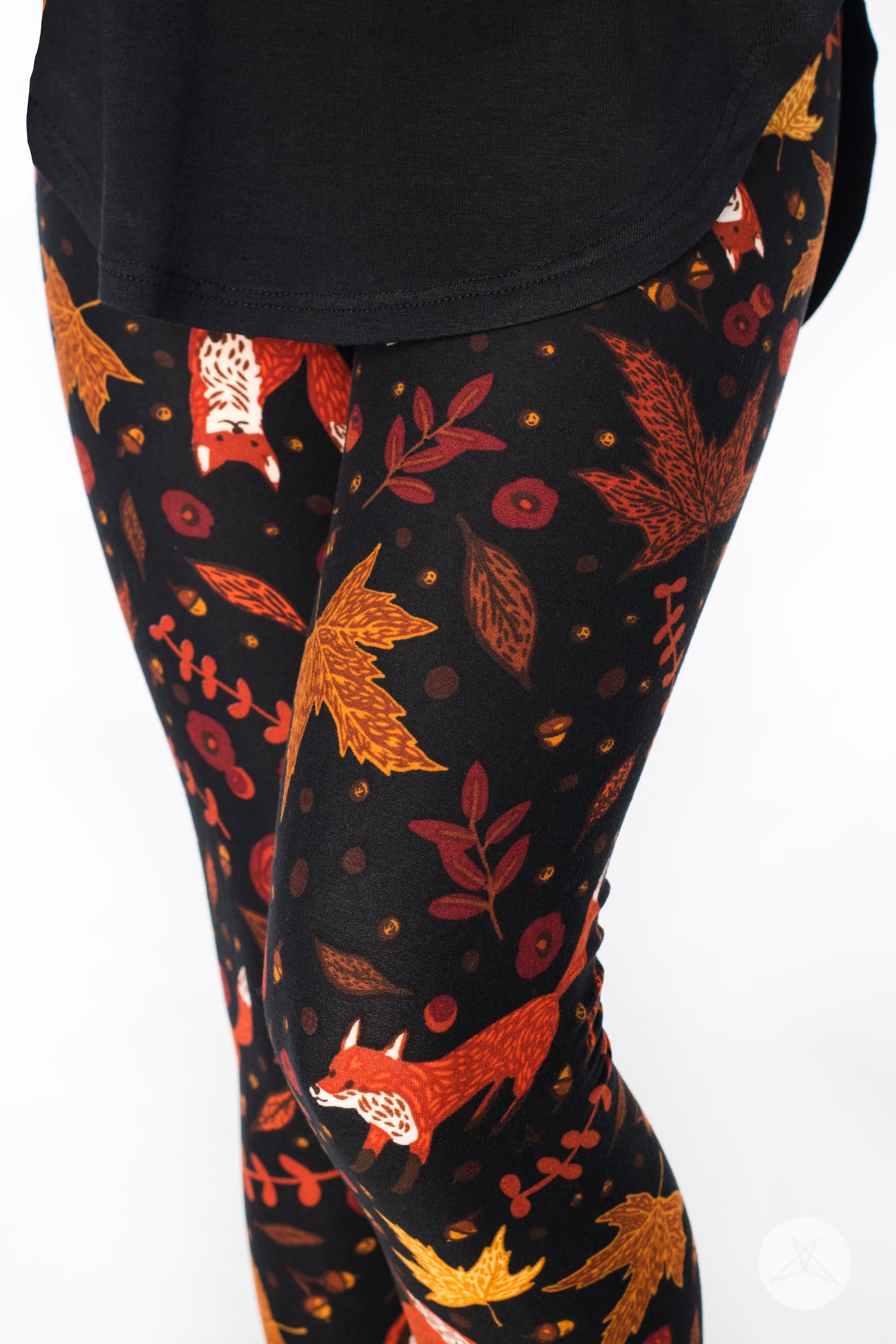 Close-up of SweetLegs Pumpkin Spice Kids leggings featuring red foxes and autumn leaves on black fabric background