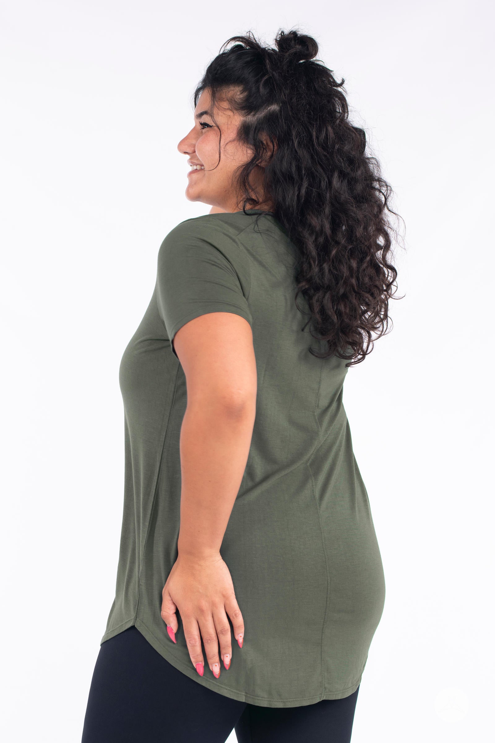 Side profile of smiling model wearing olive SweetLegs Canada Classic Tee with short sleeves and relaxed fit on white background