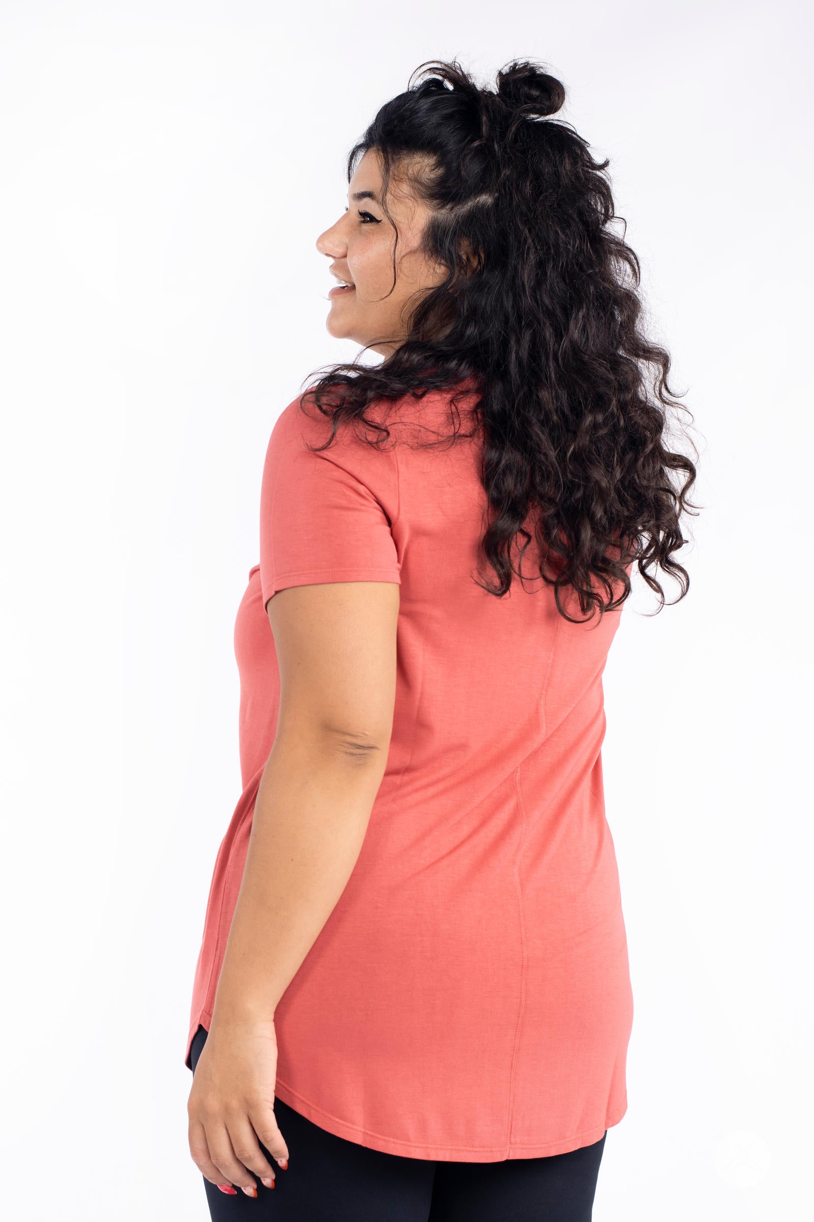 Woman wearing coral Classic Tee by SweetLegs Canada with short sleeves and high to low hem back side view